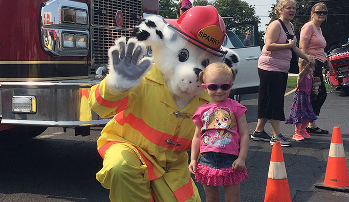 sparky mascot with child and firetruck