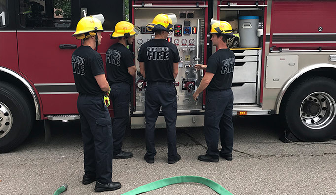 smiling firefighters in front of a firetruck