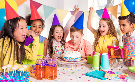 Group of kids having fun at a birthday party with cake and streamers