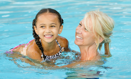 Mother and child swimming in a pool and smiling