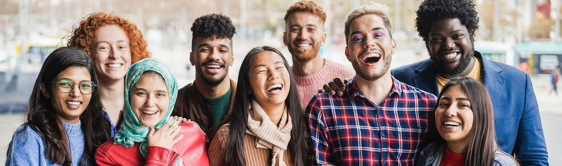 Diverse group of young people stand together smiling