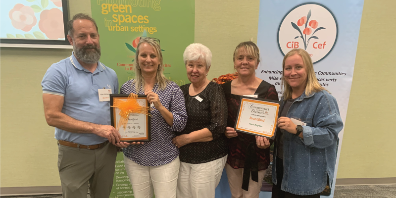 Five people standing and holding two awards received at the Communities in Bloom competition