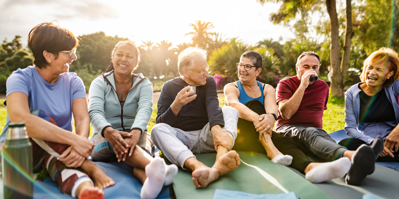 Group of seniors sit together outside during a sunset