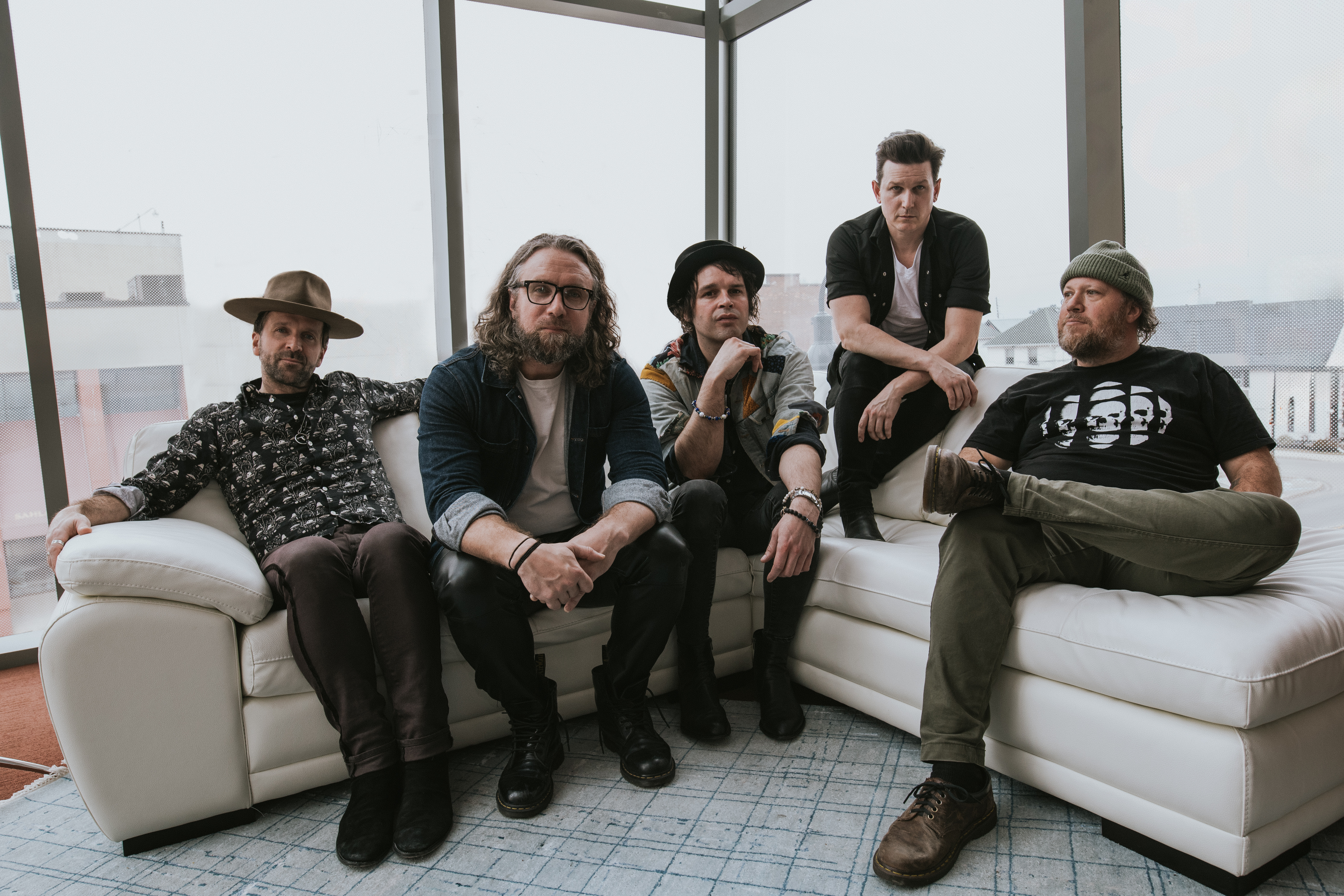 The Trews sitting on a couch by a set of windows posing.