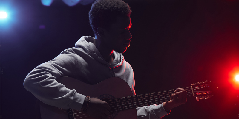 A young teen plays the guitar on stage