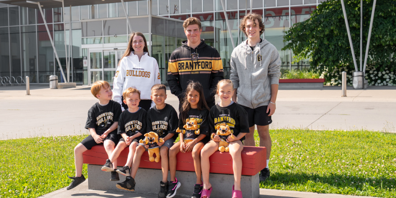 A group of young adults and kids in front of Wayne Gretzky Sports Centre wearing Brantford Bulldogs merchandise