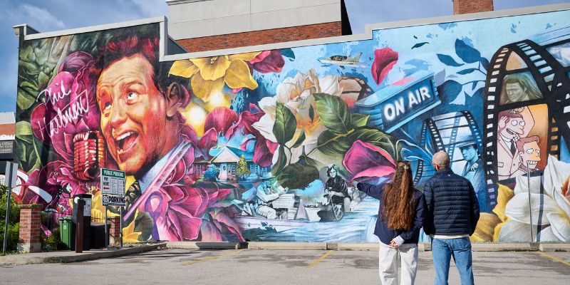 The artists from DRIFT Mural Co. standing in front of the Phil Hartman Mural